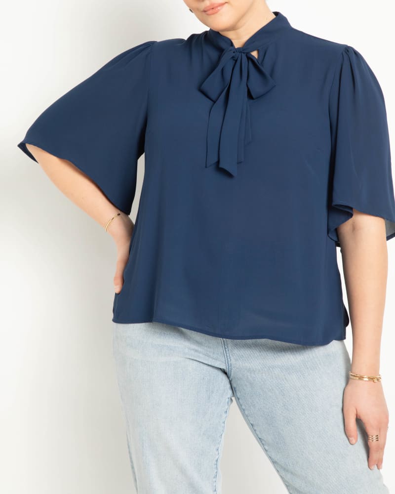 Front of a model wearing a size 20 Bow Blouse With Flutter Sleeve in Ocean Cavern by ELOQUII. | dia_product_style_image_id:284420